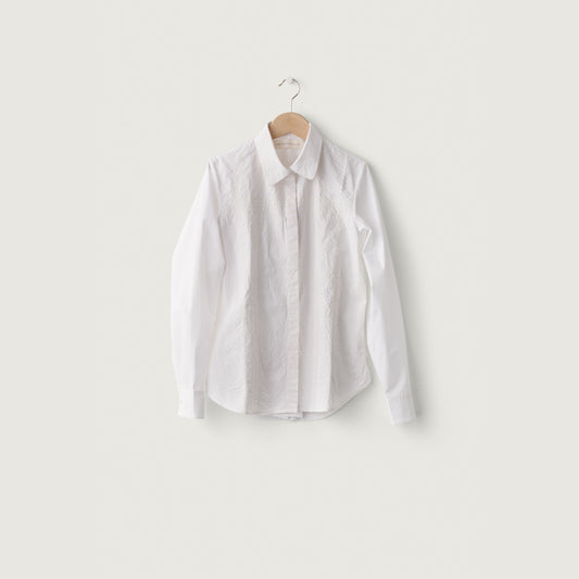 White shirt on a hanger against a light gray background