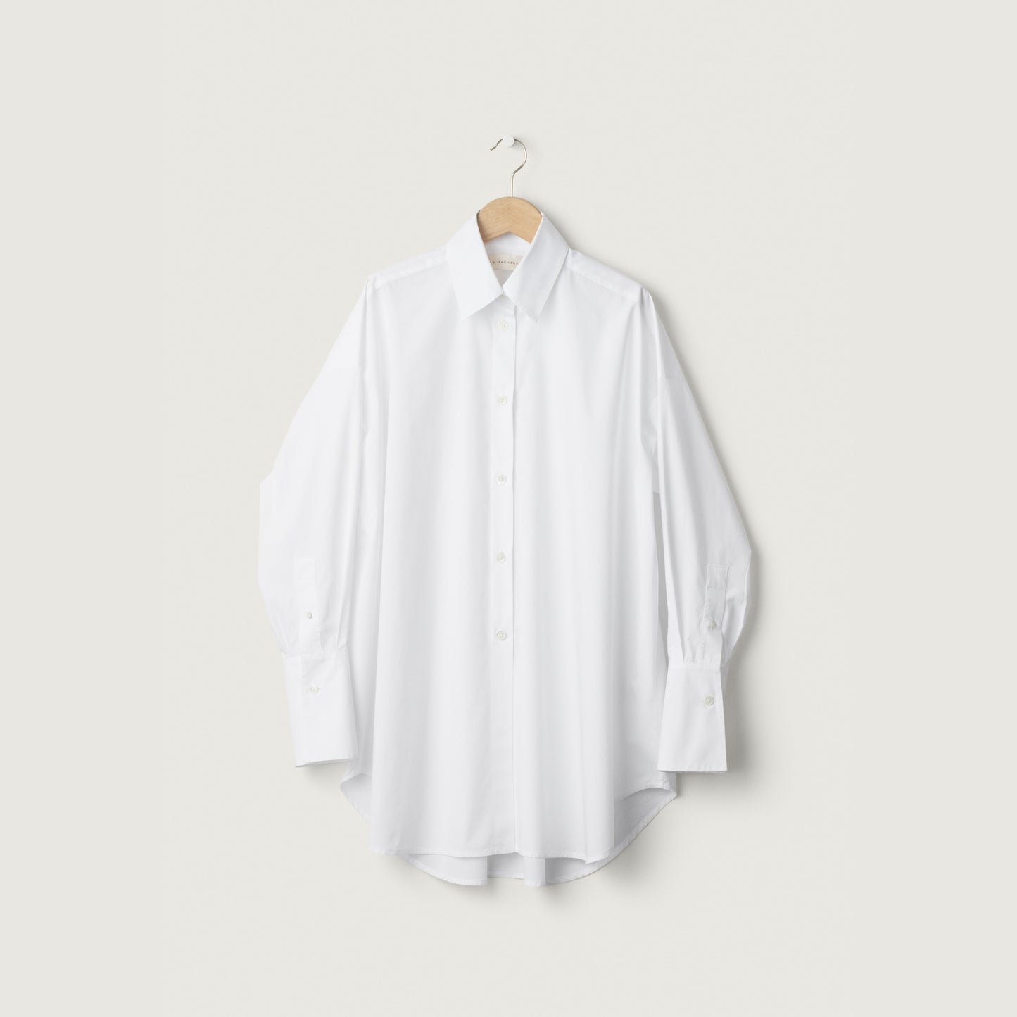 White shirt on a hanger against a light gray background