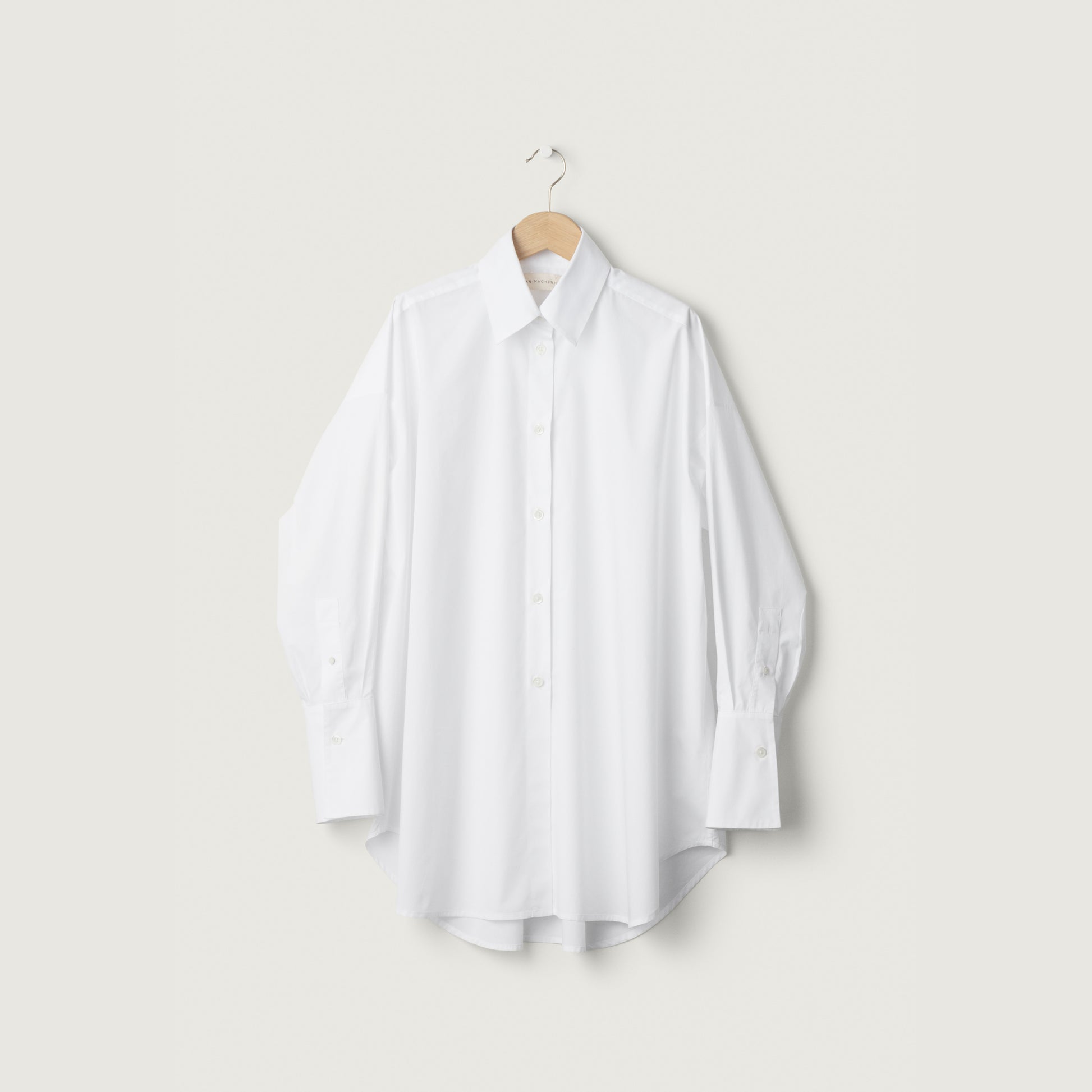 White shirt on a hanger against a light gray background